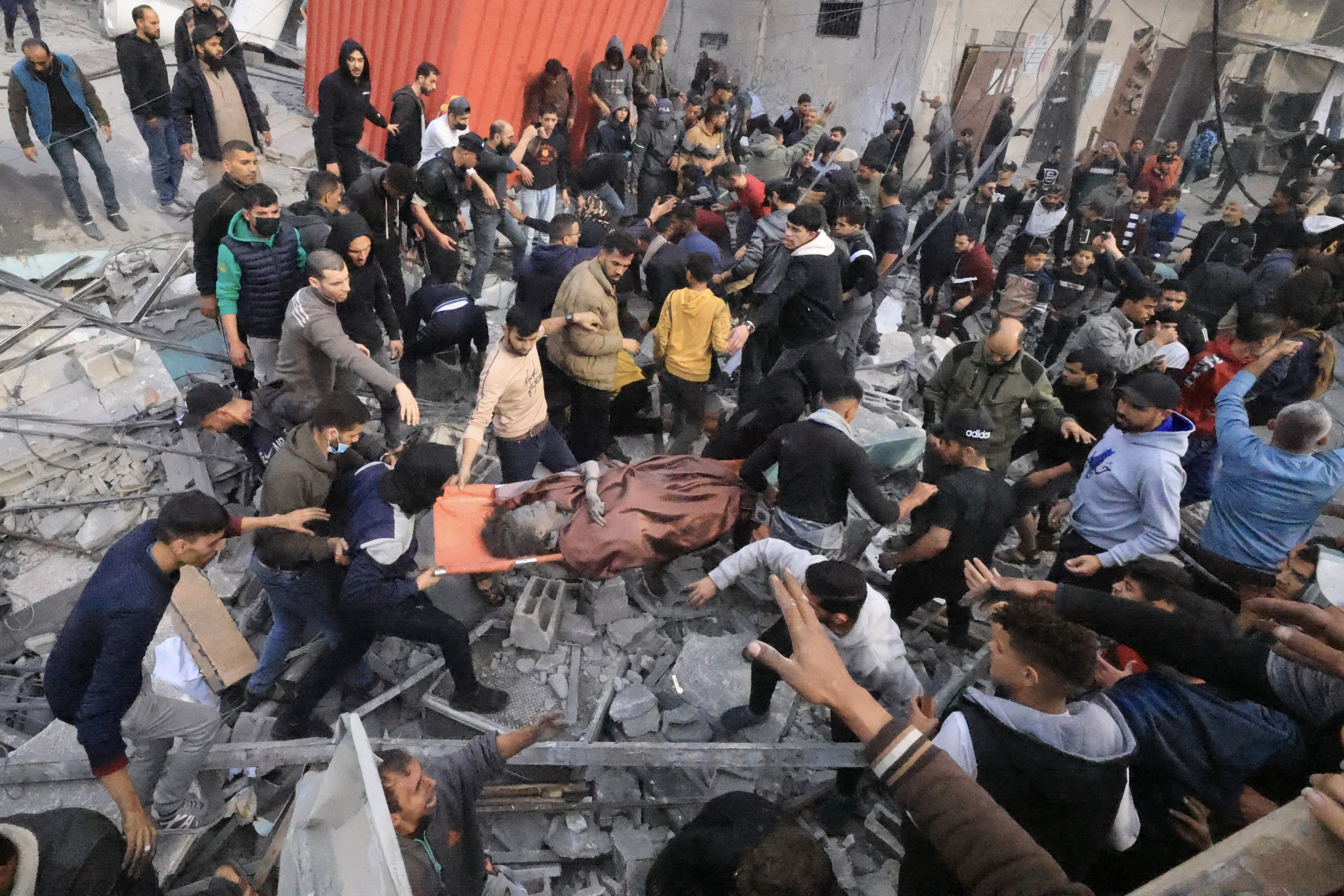 مواطنون يحاولون انتشال جثامين شهداء وإنقاذ مصابين في القصف الذي استهدف مسجدا برفح. (أ.ف.ب)